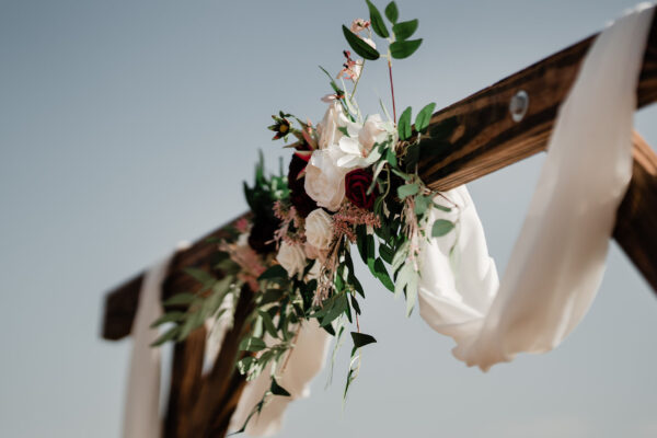 Wooden wedding ceremony arch decorated with pink flowers