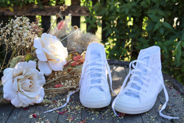 White bridal trainers with flowers at outdoor wedding
